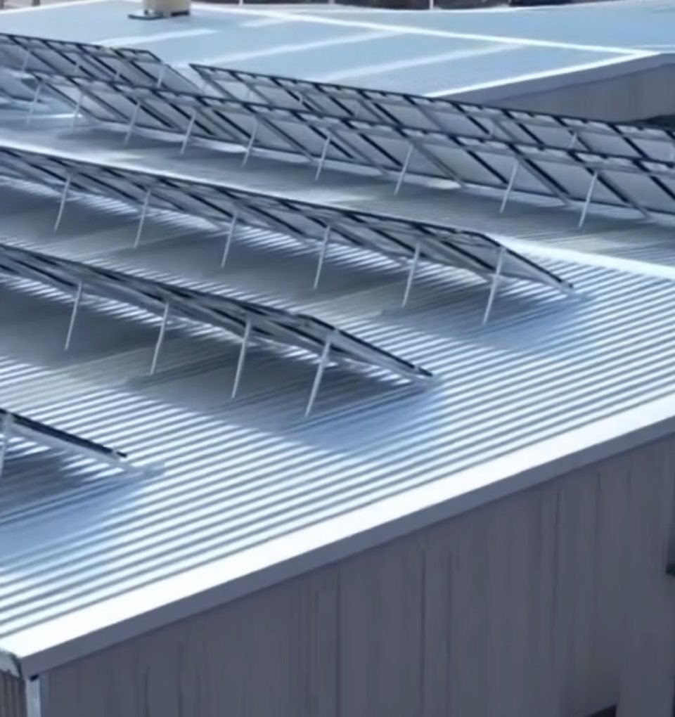Close aerial view of a new corrugated metal roof with rows of tilted solar panels
